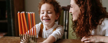 Woman and a child lighting candles for Hanukkah